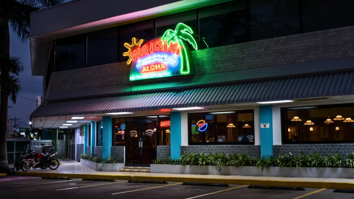 Fachada iluminada de Restaurante Waikiki por la noche